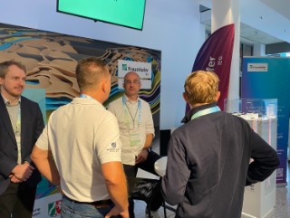 Im Foto sehen Sie Projektleiter Martin Albers (links) und Dr. Frank Sachse (rechts) am Messestand im Gespräch mit Besuchern. 
